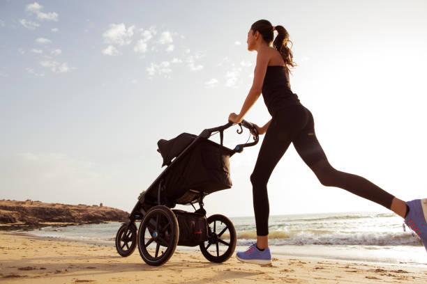 junge mutter läuft mit kinderwagen am strand. - shoe women adult baby stock-fotos und bilder
