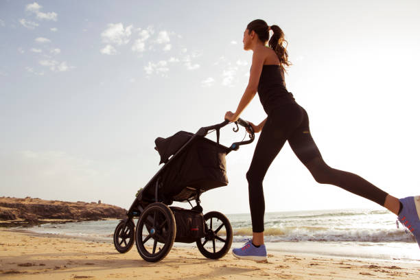 young mom is running with stroller on the beach. - shoe women adult baby imagens e fotografias de stock