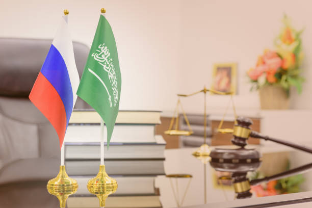 бизнес-диалог, военное и нефтяное соглашение: национальные флаги россии и саудовской аравии на столе. символ сотрудничества двух народов: м - opec стоковые фото и изображения