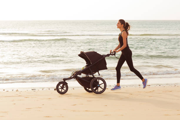 Young mom is running with stroller on the beach Sport lifestyle. animal drawn stock pictures, royalty-free photos & images