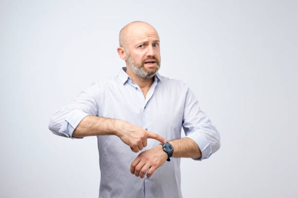 Mature european businessman impatiently pointing to his watch. Why are you late concept. Mature european businessman impatiently pointing to his watch. Why are you late concept. I am waiting here for hours. impatient stock pictures, royalty-free photos & images