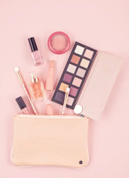 Photo of Makeup cosmetic products over pastel pink background, flat lay, top view