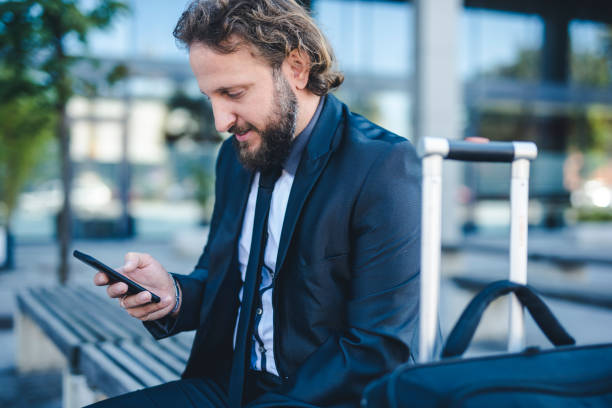 istock Businessman using smart phone at the bus stop 1046178064