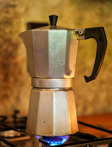 A single Moka pot brewing coffee on a stove