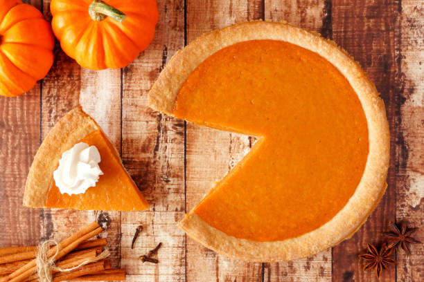 istock Pumpkin pie with slice removed, top view table scene on wood 1046187284