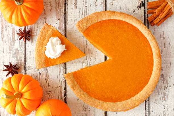 istock Pumpkin pie with slice removed, top view table scene on white wood 1046187358