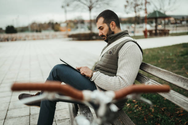 istock Fashionable man with a bicycle using digital tablet in the public park 1046207938