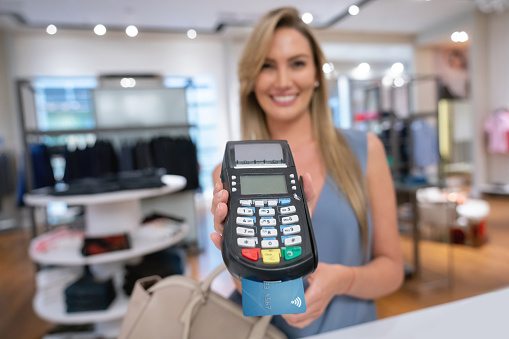 Close-up on a shopping woman paying by card at the cashier and holding the EFTPOS machine - lifestyle concepts. **DESIGN ON CREDIT CARD WAS MADE FROM SCRATCH BY US**