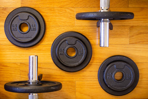 istock Dumbell Bars and Weights on Wooden Background 1046211846