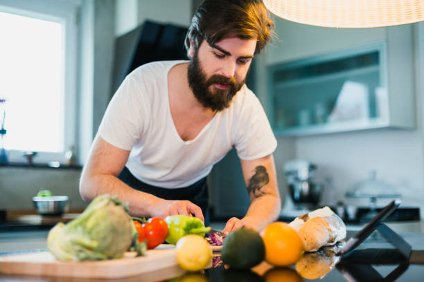 istock Handsome man cutting vegetables in the kitchen to prepare healthy dinner 1046232142