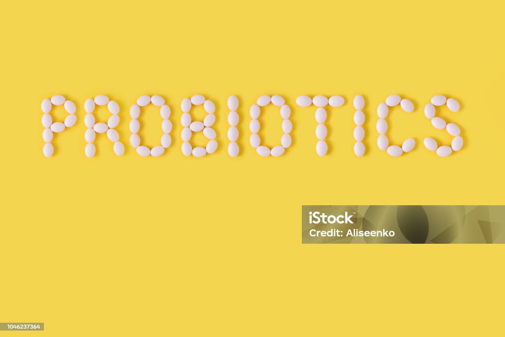 Probiotics word made of pills on yellow background. Flat lay, top view, free copy space. Probiotic Stock Photo