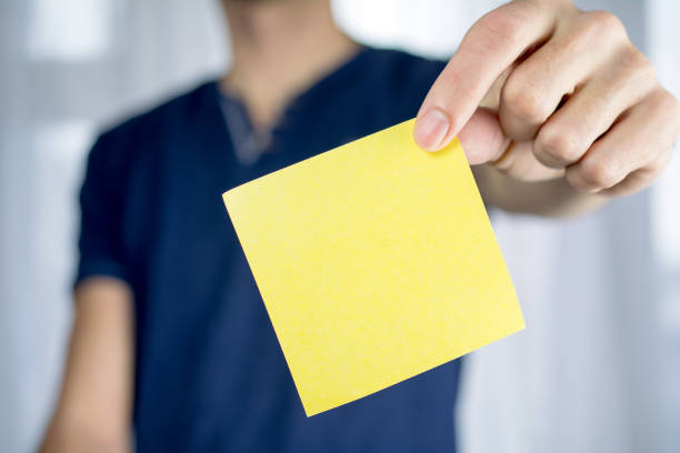 Man holds blank yellow sticker. stock photo