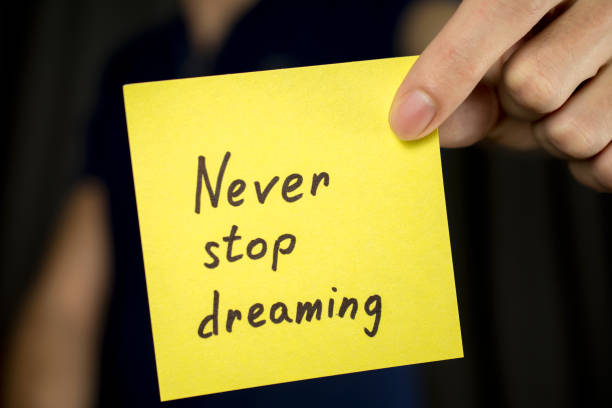 istock Man holds yellow sticker inscription Never stop dreaming. 1046252996