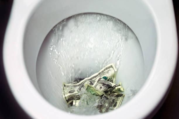 Flush money down the toilet, stock photo