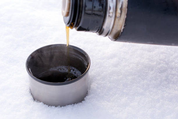 istock pours hot tea from a thermos outdoors  in the snow 1046256098