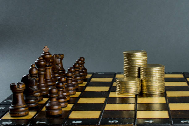 istock chess game, chess board with placed figures, piles of gold coins, 1046256580