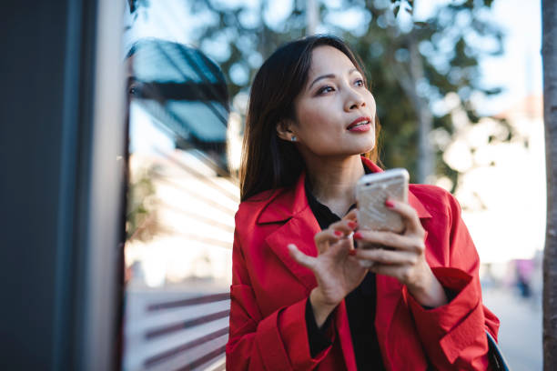 istock Businesswoman using smart phone while waiting for a bus 1046259192