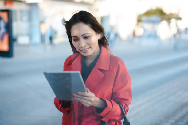 istock Businesswoman using digital tablet while waiting for a bus 1046259198