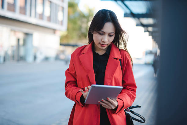 istock Businesswoman using digital tablet while waiting for a bus 1046259220