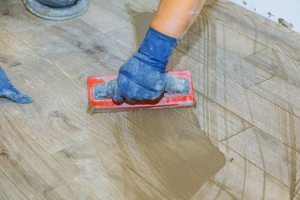 Hand of flooring on gray color of new grout tile on tile gray for the final step for flooring Hand of flooring on gray color of new grout tile on tile gray for the final step for flooring smoothing tile joints with a sponge travertine pool photos stock pictures, royalty-free photos & images