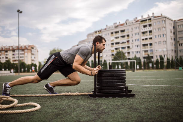 young man doing sled pushing workout outdoors - playing field effort outdoors human age imagens e fotografias de stock