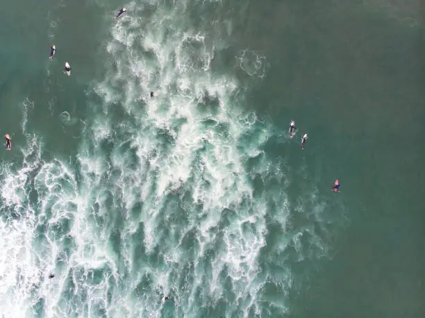 Photo of View of Praia do Guincho, Guincho beach, a popular Atlantic Ocean beach on Portugal's Estoril coast, municipality of Cascais, with surfers surfing on the waves, shot from drone