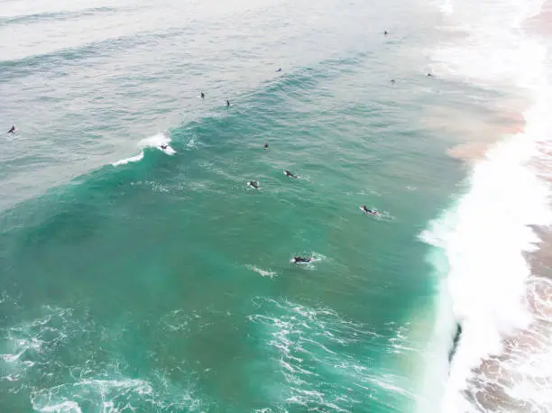 Photo of View of Praia do Guincho, Guincho beach, a popular Atlantic Ocean beach on Portugal's Estoril coast, municipality of Cascais, with surfers surfing on the waves, shot from drone