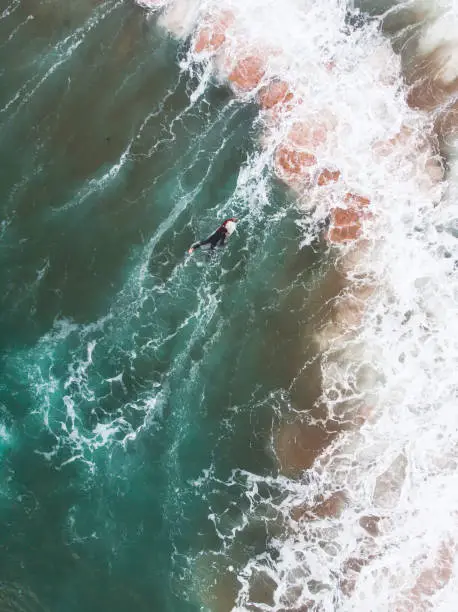 Photo of View of Praia do Guincho, Guincho beach, a popular Atlantic Ocean beach on Portugal's Estoril coast, municipality of Cascais, with surfers surfing on the waves, shot from drone