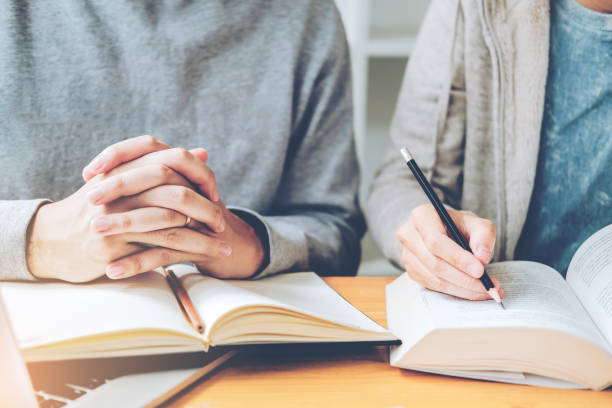 istock High school or college students studying and reading together in library 1046283508