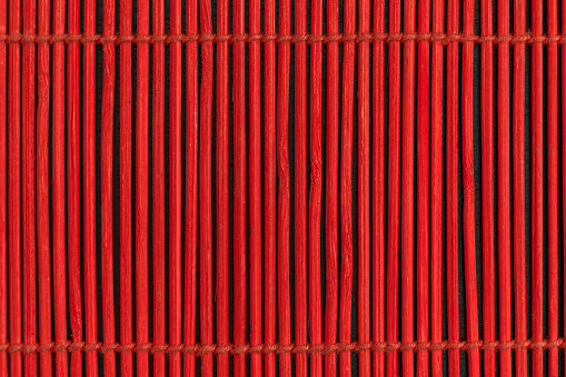 Red sticks in dark background. Red sticks tied up between each other with the rope
