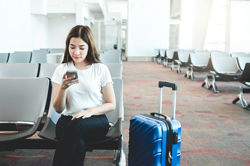 Tourist Women using Phone at international airport waiting for boarding