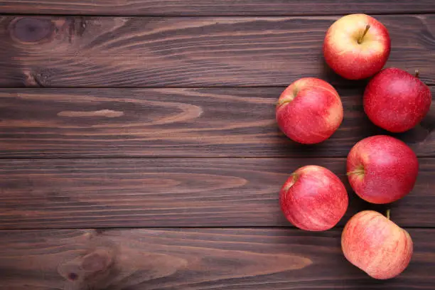 Fresh red apples on a brown wooden background