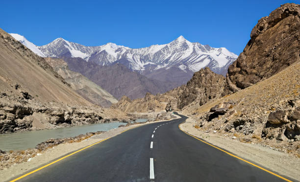 ladakh szenische landstraße straße mit kahlen berge und ferne schnee gipfel himalajagebirgszüge. - indian peaks stock-fotos und bilder