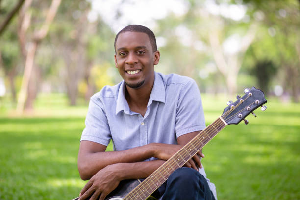 sourire noir guitariste avec la guitare dans le parc - musical instrument nature outdoors musician photos et images de collection