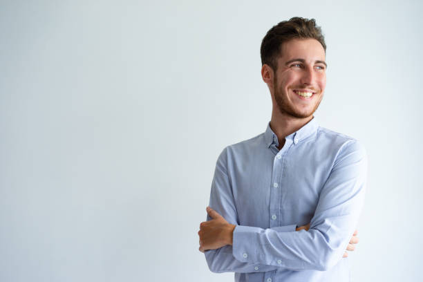 Cheerful businessman enjoying success Cheerful businessman enjoying success. Young man in office shirt folding arms, looking away and smiling. Business success concept dressing up photos stock pictures, royalty-free photos & images