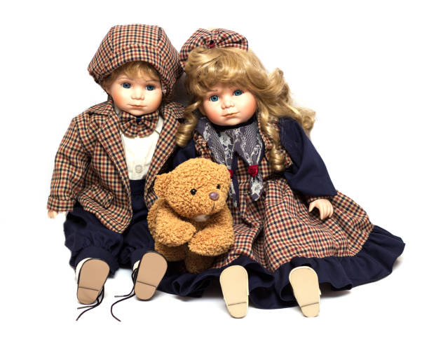 istock Two old, ceramic dolls and a teddy bear. Old porcelain doll on White Background 1046350956