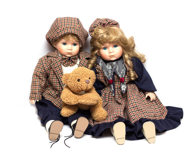 istock Two old, ceramic dolls and a teddy bear. Old porcelain doll on White Background 1046351352