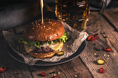 Tasty burger and mug of beer on wooden table