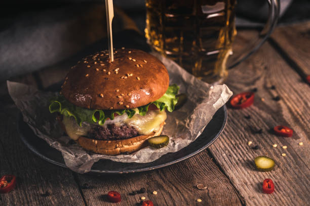 smaczny burger i kubek piwa na drewnianym stole - sandwich plate food french fries zdjęcia i obrazy z banku zdjęć