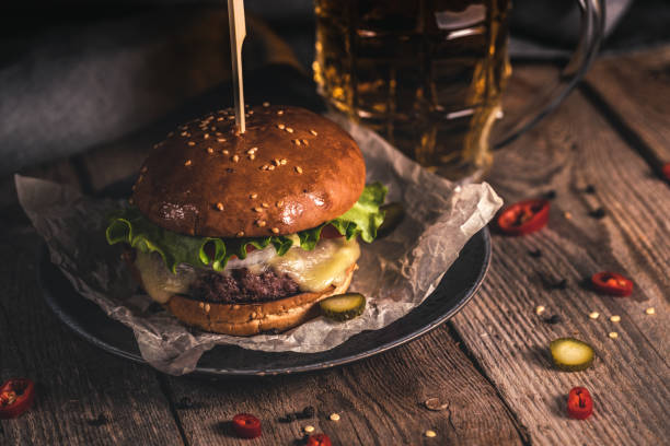 hambúrguer saboroso e caneca de cerveja na mesa de madeira - burger gourmet hamburger steak - fotografias e filmes do acervo