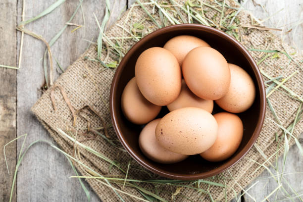 istock in a clay plate of raw red farm eggs in straw. 1046366342