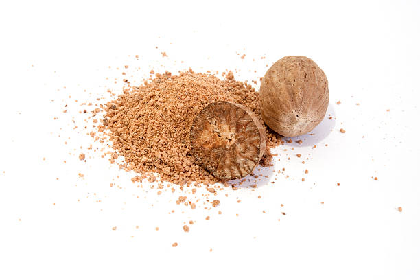 A close-up of whole nutmeg and crushed nutmeg Whole and grated nutmeg isolated on white background nutmeg stock pictures, royalty-free photos & images