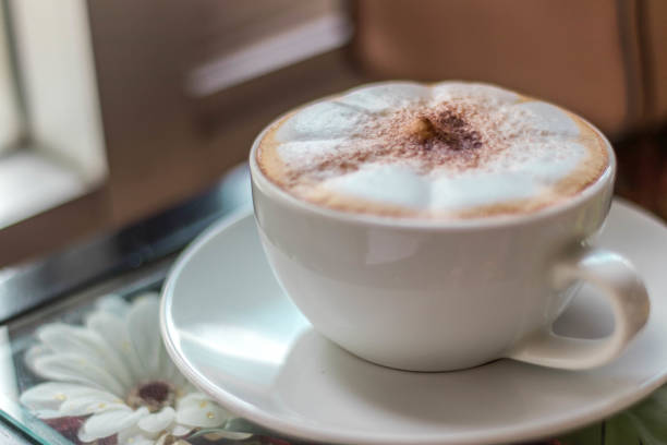 istock Cappuccino coffee on wooden table and sunlight background 1046369488