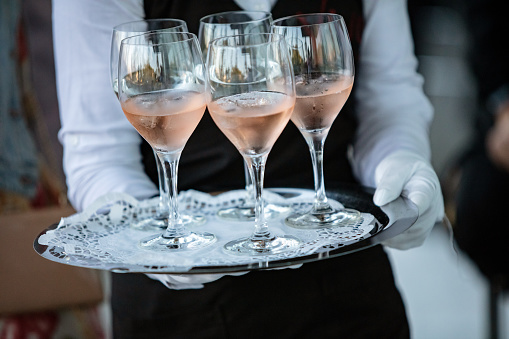 Waiter serving rose wine