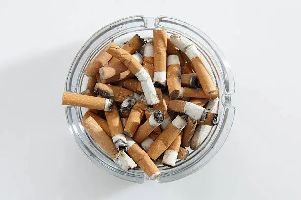 overhead view of glass ashtray full of cigarette stubs