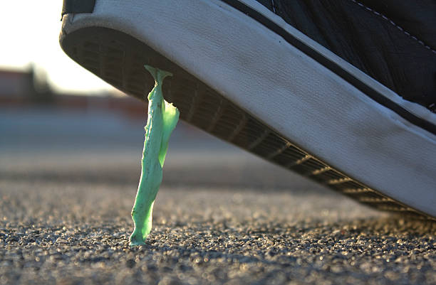 A vertical shot of the white dirty sneakers hanging from the street wire on an asphalt road background