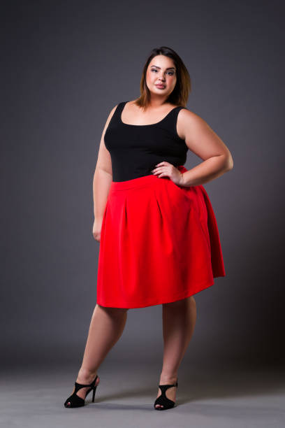 plus size mode-modell im roten rock, fette frau auf grauem hintergrund übergewicht weiblichen körper - dress full length women sensuality stock-fotos und bilder