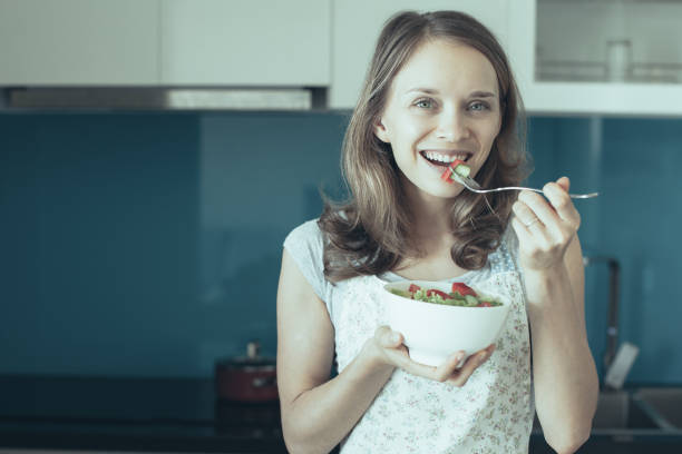 istock Happy Woman Eating Vegetable Salad in Kitchen 1046383040