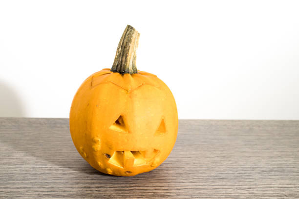 istock Scary orange halloween pumpkin on a wood table composition 1046383336