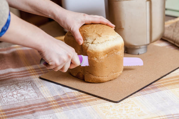 istock Hostess cuts loaf of bread with big knife 1046383438